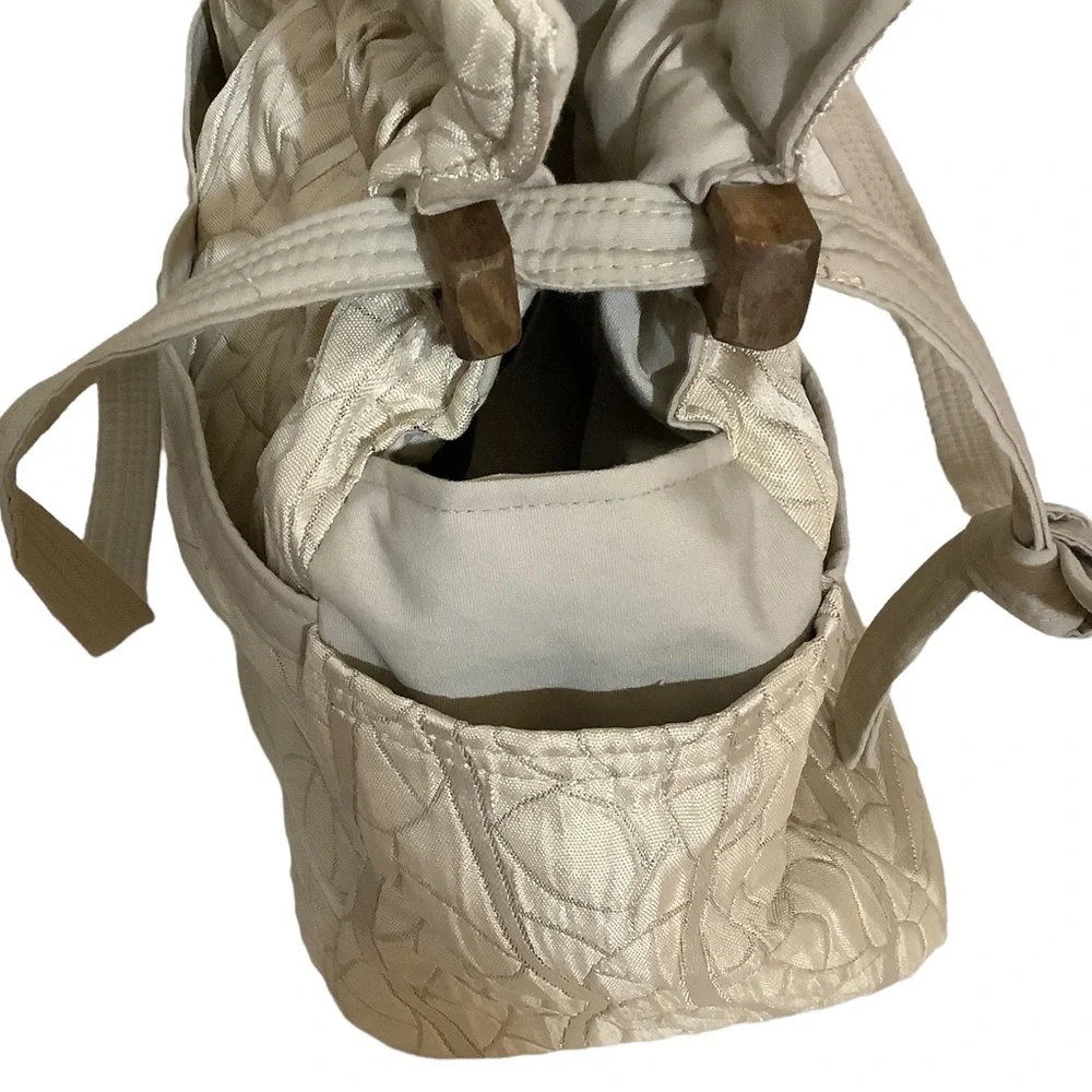FABRIC SHOULDER BAG WITH OUTSIDE SURROUNDING POCKETS IN A CREAM AND TAUPE COLOR.